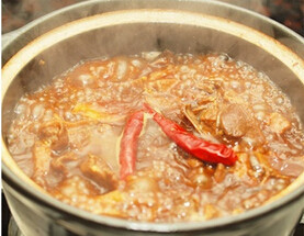 干锅莲藕鸭,下姜片、葱段和蒜蓉,爆香,转中火,下鸭肉煸炒至鸭肉的皮变金黄