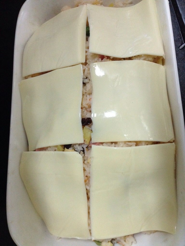 菠萝海鲜焗饭,如图，把飯裝入焗盤里，鋪上<a style='color:red;display:inline-block;' href='/shicai/ 62159'>芝士片</a>。烤箱預熱3分鐘，150度焗10分鐘。