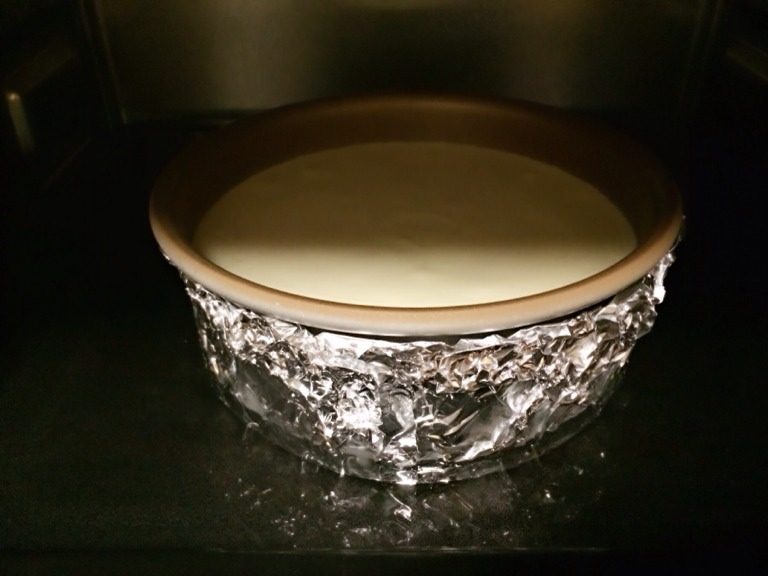 轻乳酪蛋糕,把蛋糕糊倒入模具,双手握住模具两边轻轻上下磕几下,蛋糕液里的大气泡会升上来破掉,这样做出的蛋糕会更细腻。把烤盘加1.5厘米的水,190度上下火预热5分钟。放进模具,调整成170度烤制80-90分钟。这种方法叫水浴法。