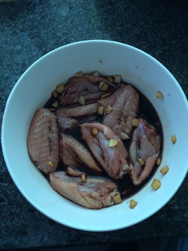 可乐鸡翅（电饭锅版）,翅中、蒜姜放在碗里，加入<a style='color:red;display:inline-block;' href='/shicai/ 692'>酱油</a>，炮制二十分钟。<a style='color:red;display:inline-block;' href='/shicai/ 692'>酱油</a>刚盖过翅中就好，太多会咸。