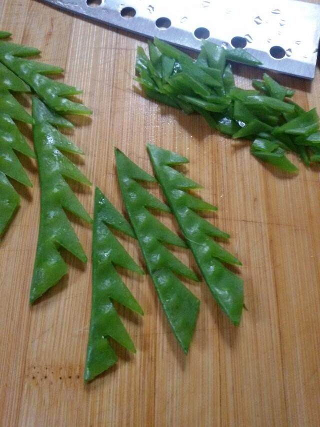 花开牡丹虾,荷兰豆用刀切成花叶形,放入盐开水焯水捞出。