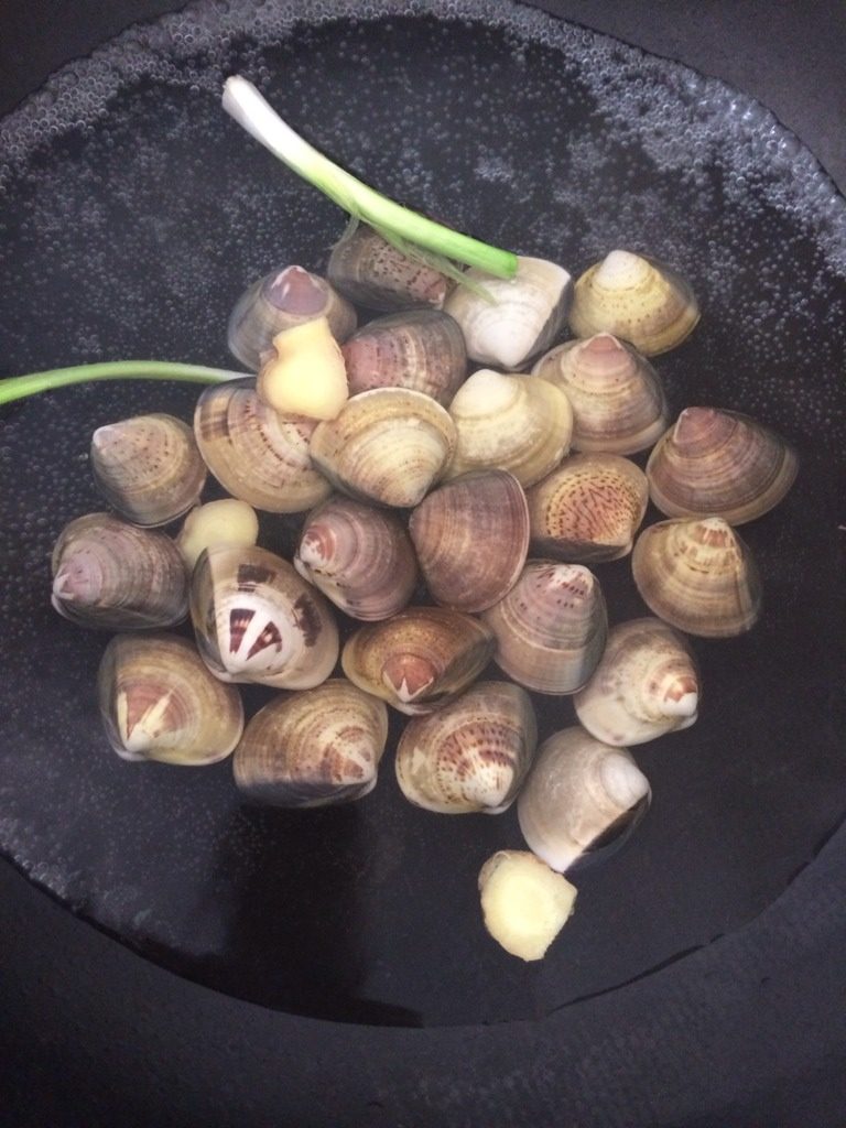 蛤蜊蒸蛋,把蛤蜊用水泡两小时,吐出脏东西,然后刷干净。锅里放一碗水,加入葱白和姜片。倒入蛤蜊