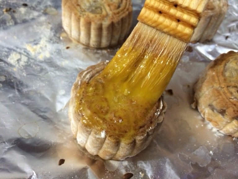 广式月饼,取出烤盘，给月饼表面刷蛋黄液，再次放入烤箱15分钟左右至金黄色