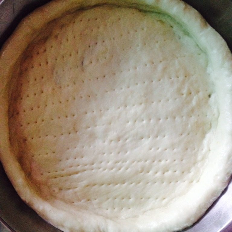 培根蘑菇海鲜披萨,如图，饼团用叉子叉出小孔