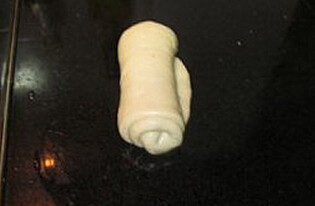 牛奶吐司,揉好后的面团均分成二等份，松驰15分钟，碾成长舌状，再由上往下卷成圆柱形