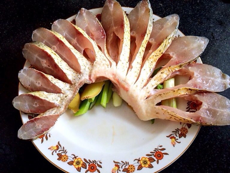 凤凰于飞--清蒸鱼,倒掉料酒,盘子中央铺葱段姜片,鱼中段摆成扇形