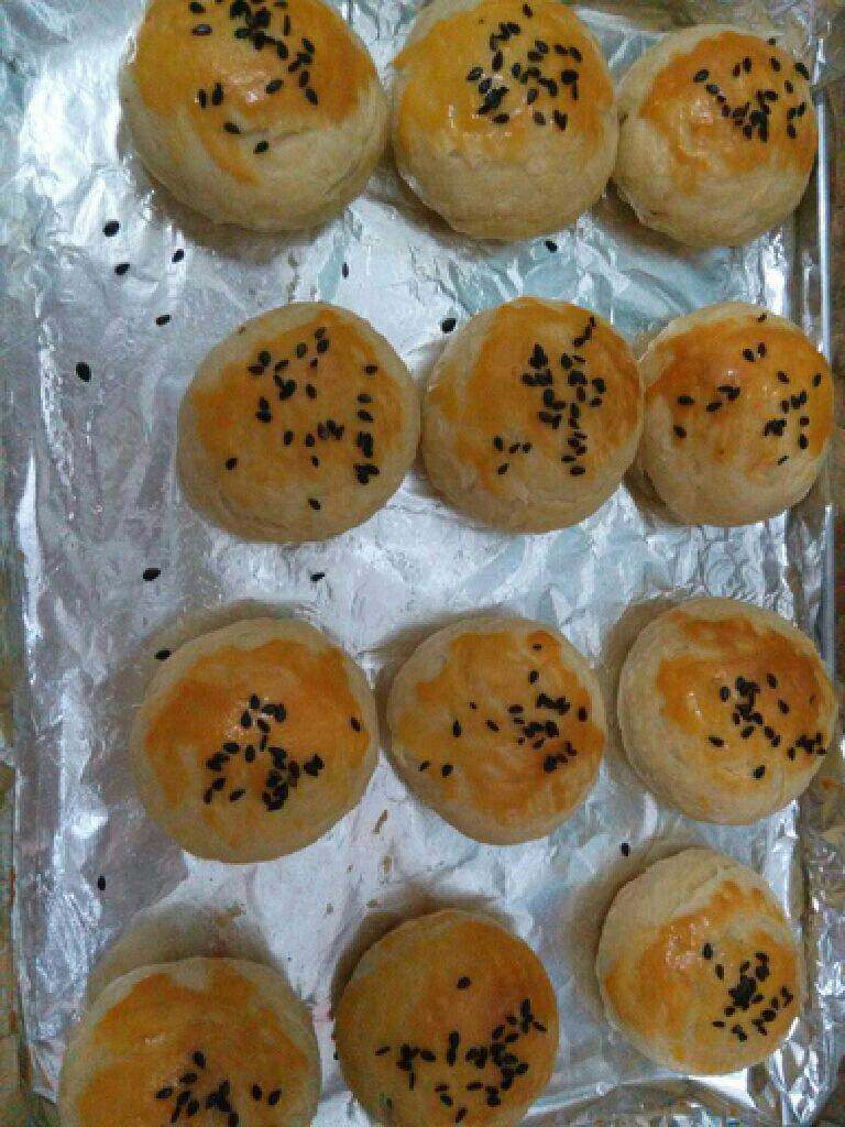 苏式梅干菜月饼,取一个面团按平擀成薄片包入馅料。收口处朝下。刷上蛋黄液。撒上芝麻,烤箱180℃预热 烤30分钟表面金黄即可