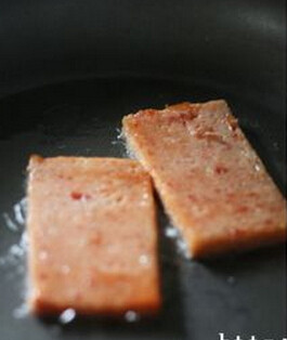 港式餐蛋面,将午餐肉切成厚片,取两片在煎锅里用少许油煎至两面金黄,取出备用;