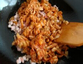 韩国辣白菜炒饭,锅内再放油，放入肉丁爆熟，加入辣白菜丁和辣白汁翻炒