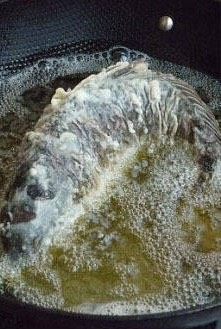 糖醋鲤鱼,锅内放入足够多油,七成热时将鱼弯成弧形放入,小火炸,炸时可以用两只锅铲按住鲤鱼定形