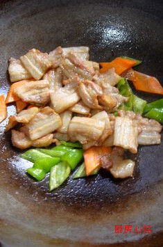 自制培根小炒肉,油锅下入胡萝卜片；青椒片爆出香味，下肉片