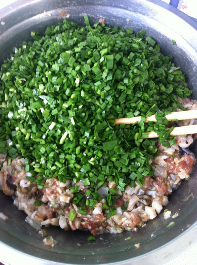 海螺馅饺子,如图 放入切好的韭菜末,倒入食用油搅匀。