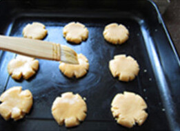 全麦桃,将小球压扁，中间略凹、四周自然裂开；扫上薄薄一层蛋液