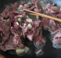 沙茶牛肉焖面,把切好的牛肉片放入不粘锅煎,放入蒜片,辣椒煎至牛肉片两面都变色即可