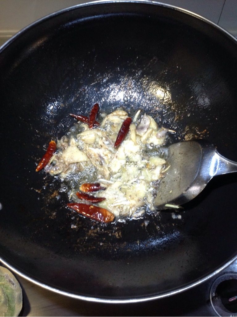 擂茶手撕鸡,锅内入油,大火热油后关火,待油温稍降将干红椒、姜蒜丝入锅,料出香后再将鸡皮入锅,用中火滑炒,鸡皮表面出油起皱即可调小火