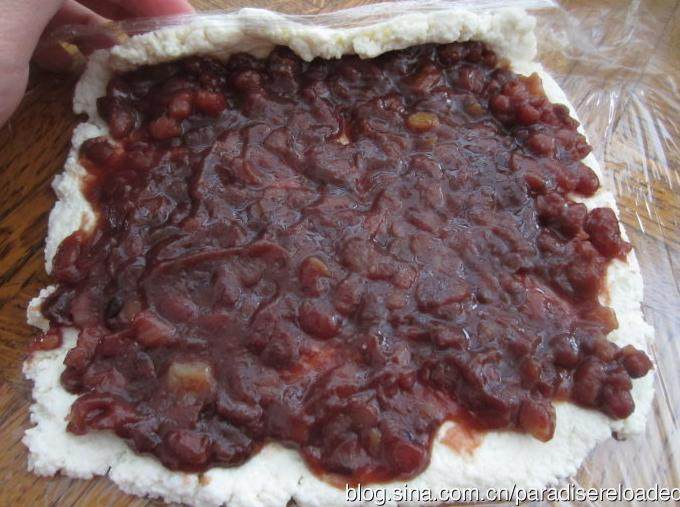红豆奶酪卷,保鲜膜上平铺挤干的乳酪，乳酪上抹上一层<a style='color:red;display:inline-block;' href='/shicai/ 475'>红豆沙</a>，卷起保鲜膜，扎紧两端。