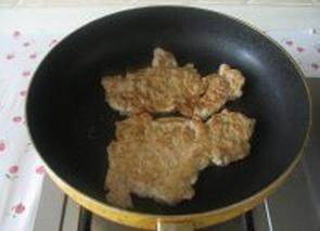 日式猪排饭,平底锅中放入适量色拉油,将猪排平铺入中火煎至两面金黄色盛出放在一旁