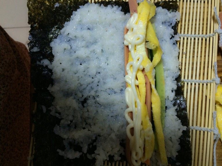 紫菜包饭,将<a style='color:red;display:inline-block;' href='/shicai/ 279'>海苔</a>铺底均匀的铺上一层米饭，依次将上述条形食材靠一边放好，挤上<a style='color:red;display:inline-block;' href='/shicai/ 4856'>沙拉酱</a>