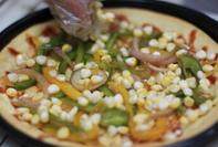 蔬菜培根披萨,饼底考好以后拿出铺上蔬菜，中间加入芝士，然后在最上面再铺上一层芝士再烤