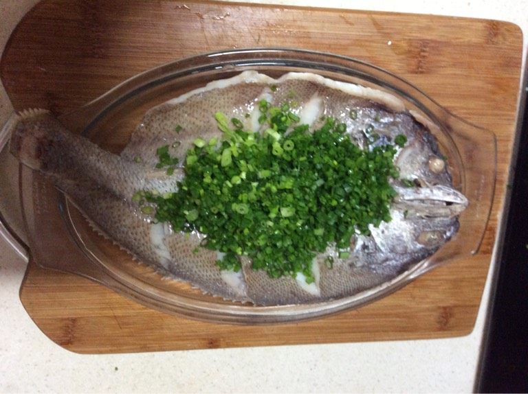 新手级别宴客菜 油葱鮸鱼,如图鱼出锅后倒去盘内蒸鱼后所留汤汁,并把底下葱白段抽出,铺上葱末