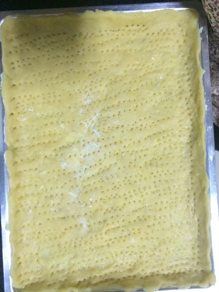 奶油椰香南瓜派,将醒发好的派皮擀成薄片均匀放至烤盘中,用叉子扎出小孔,防止烘烤时起泡,准备就绪放入180度预热好的烤箱,中层,烘烤15分钟