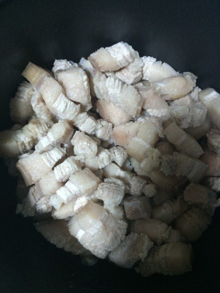 自制卤肉饭,如图将抄水过的五花肉放入锅中不加油,干煸,煸至出油,肉表面金黄