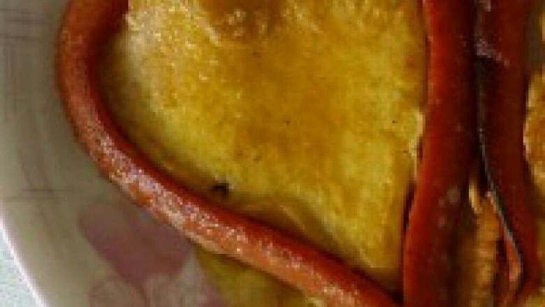 我的爱心早餐【火腿肠煎鸡蛋饼】,锅里放适量油把固定好的火腿放进锅里，在把搅拌好的鸡蛋倒入火腿肠的中间用小火慢慢煎。
