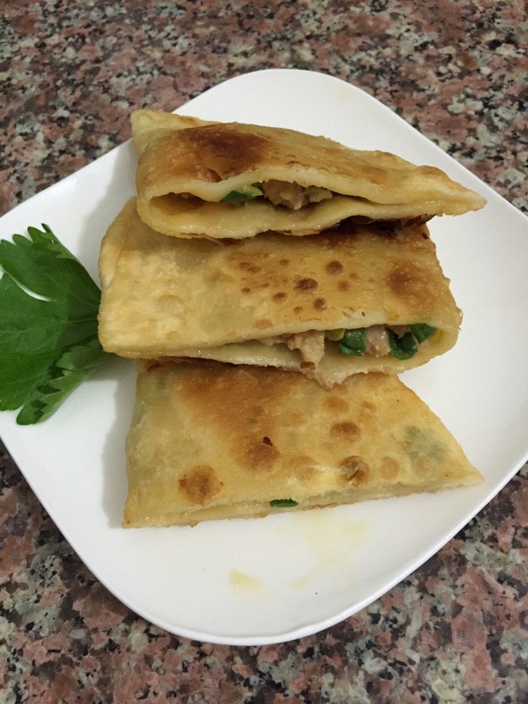 葱花猪肉馅饼,出盘放在铺好的厨房用纸上面,切两半就可以吃了。
