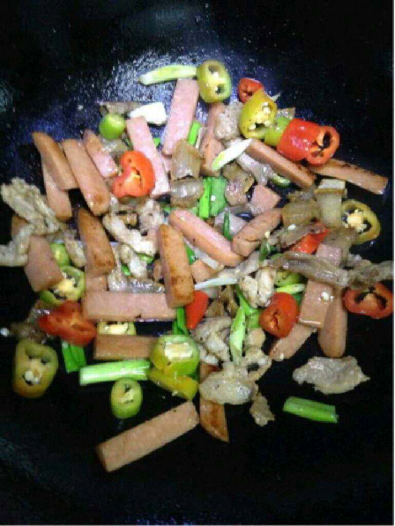 火腿肠炒肉片,翻炒均匀后加入适量生抽和盐调味。