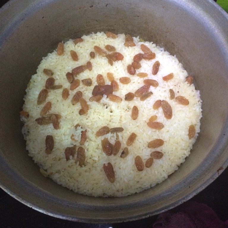 羊肉手抓饭,如图打开锅盖看表面米是否熟透,如果还有硬芯儿可以继续加盖焖煮,若表面米饭熟透无多余水分可翻炒均匀,停火加盖闷五分钟,让热气将米中的水分吸收均匀