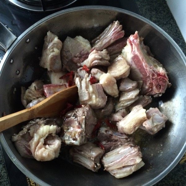 羊肉焖饼子,将肉翻炒,肉变白,将肉中的油炒出来,肉周围变成金黄色