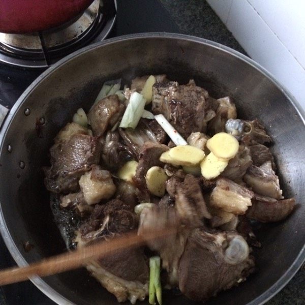 羊肉焖饼子,放入葱姜蒜,再放入老抽调色,再翻炒一会,后倒入适量开水。
