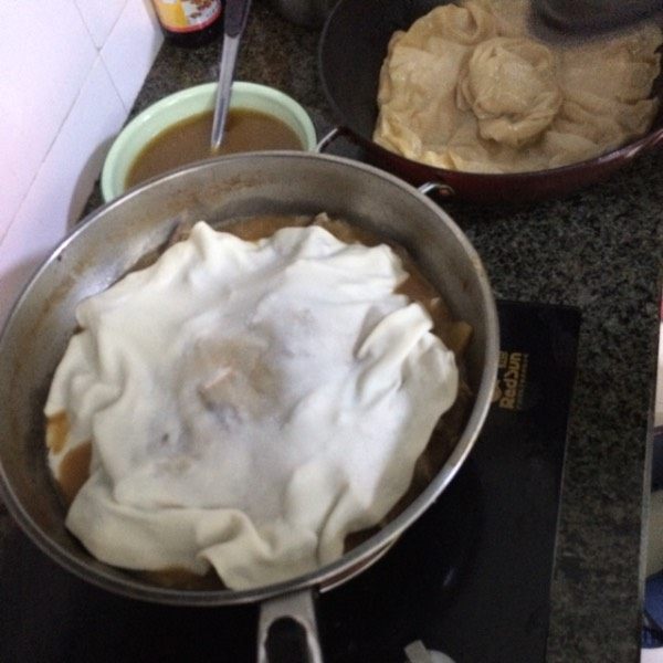 羊肉焖饼子,将锅中炖肉的汤汁乘出来一碗备用,将薄饼放到肉上面,然后把锅盖盖上焖,饼子越薄,焖的时间就越短,大概一分钟后。
