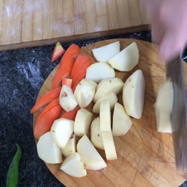羊肉焖饼子,饼子好了以后,将胡萝卜和土豆切成滚刀块,不能太小,将切好的胡萝卜和土豆放到肉里,翻炒几下。