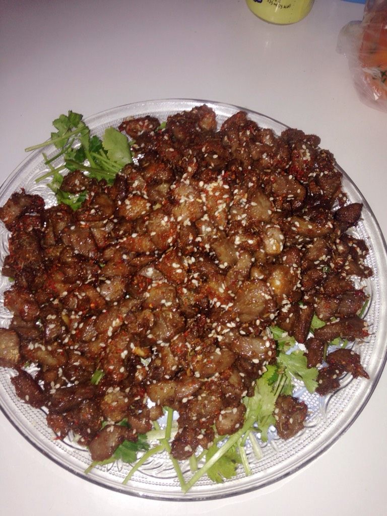 孜然羊肉,第二遍油温90左右 分少量下锅 变为深色出货沥油后放厨房用纸上吸油 撒孜然辣椒面芝麻 多次分批炸完放完调料 统一装盘子 盘子上可垫香菜或生菜 即可