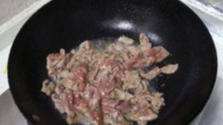 葱爆羊肉,上锅烧油,5成热的时候将腌制好的羊腿肉下锅,翻炒泛白之后就盛出。