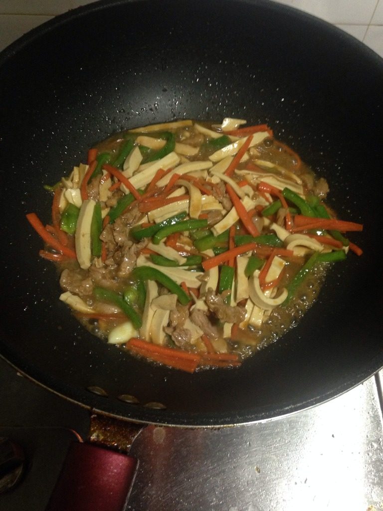 青椒萝卜炒豆干肉丝,如图倒入猪肉丝,加入适量的水,盖上锅盖。三分钟。