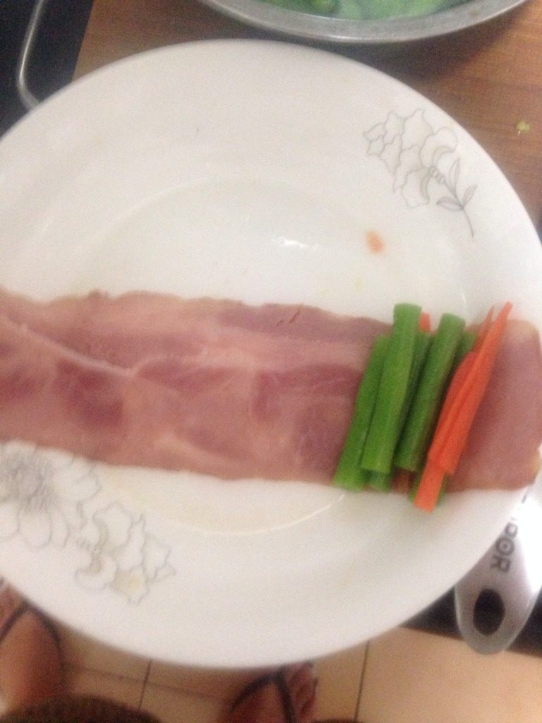 培根豆角卷,如图豆角、胡萝卜丝放在煎好的培根上，卷起来。
