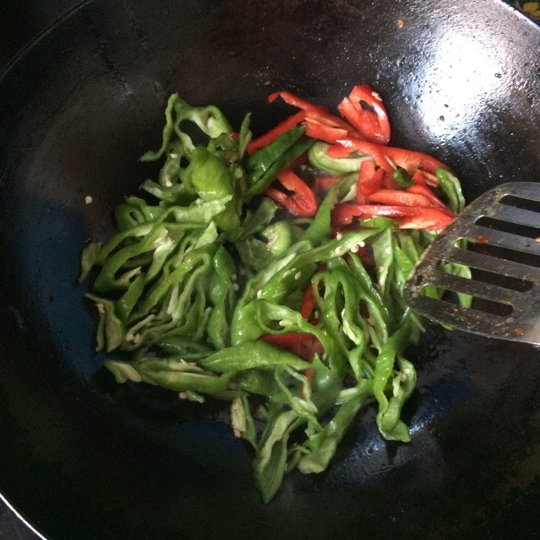 辣椒抱鸡蛋,如图锅里倒入适量的食用油,油热后倒入青红椒丝和葱花
