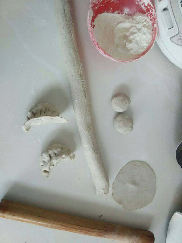 酸菜猪肉馅饺子,现在来和面，将面粉放入盆中倒入适量的水，用筷子搅拌成棉絮状后用手揉成面团，盖好盖子放置一会，把桌子撒上少许面粉把面团拿出开始揉面团，把面团揉成如图一样后揪成小面团开始擀面饼，如图所示擀成的面饼包入馅料包成饺子，把包好的饺子下入锅中煮熟就可以吃到香喷喷滴饺子啦
