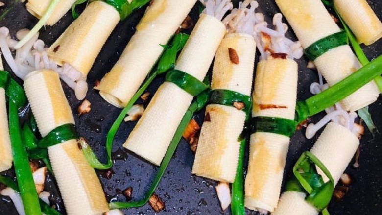 金针菇豆皮卷,锅中放油,油热以后放入豆皮卷轻轻翻炒一下,把刚才调的酱汁倒进锅中。如果酱汁太少可适当加水。