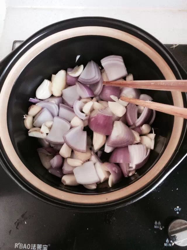 生啫鸡煲,油七成热放入准备好的洋葱蒜粒,姜片,翻炒