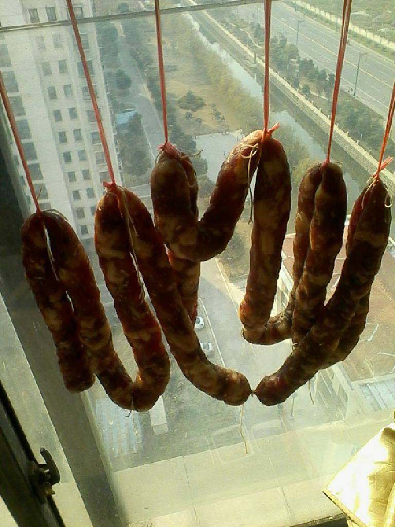 自制川味腊肠,将灌好的肉肠用温水清洗干净表面。吊起放阳台晒7至lO天,阴干也可以时间长些