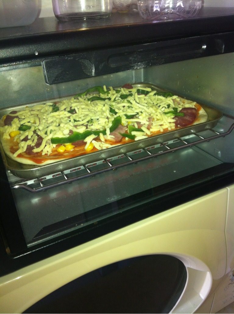 自制培根披萨,先用<a style='color:red;display:inline-block;' href='/shicai/ 219'>牛奶</a>和面'把面发起来噢'然后把面杆到烤箱盘大小'放进烤箱'把喜欢的材料放到面上'我放的腊肠'培根'玉米粒'青椒'然后撒上厚厚一层芝士碎噢'放烤箱烤12分钟