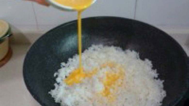 五彩冰芬【圣诞炒饭】,米饭炒得比较干爽时,淋入打散 的鸡蛋液继续翻炒。