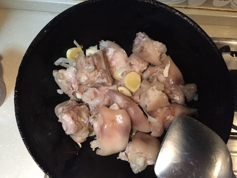 猪手焖黄豆,炒锅放油把葱姜蒜放入煸炒出香味，放入猪手大火不停地煸炒