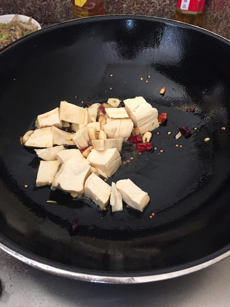 鱼子焖豆腐,锅里放油,加入大蒜、干辣椒豆腐入锅翻炒