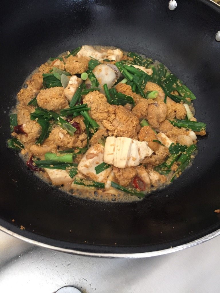 鱼子焖豆腐,加入适量调味料,加入少许清水,放入青蒜,盖上锅盖小火焖五分钟