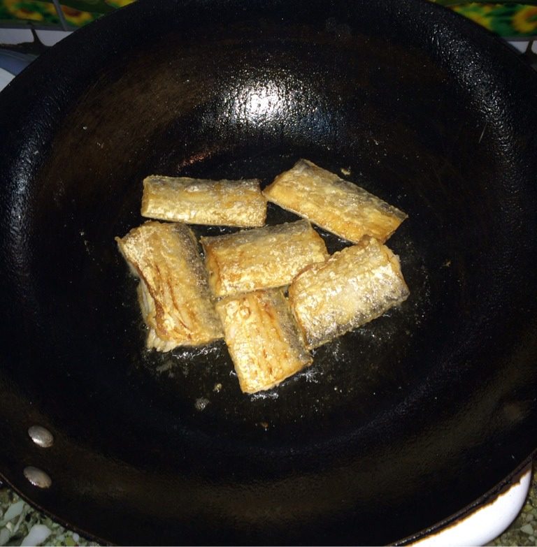 带鱼炖豆腐,油锅烧热,将鱼段两侧粘上面粉,再下油锅,煎至金黄