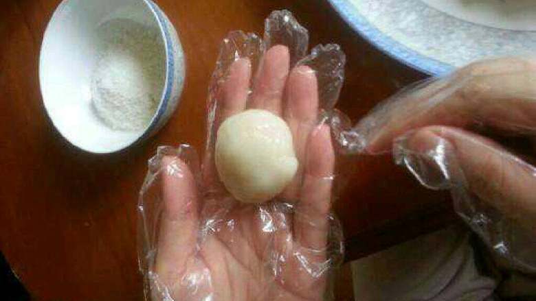 自制【芒果糯米糍】,蒸好了拿出来，戴上一次性手套，手套上摸一点油，弄一点蒸好的糯米粉放手里，揉成圆形。